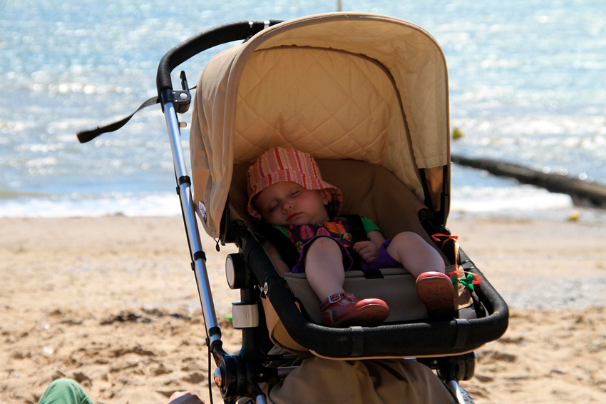 niña durmiendo dentro de su carrito en la playa